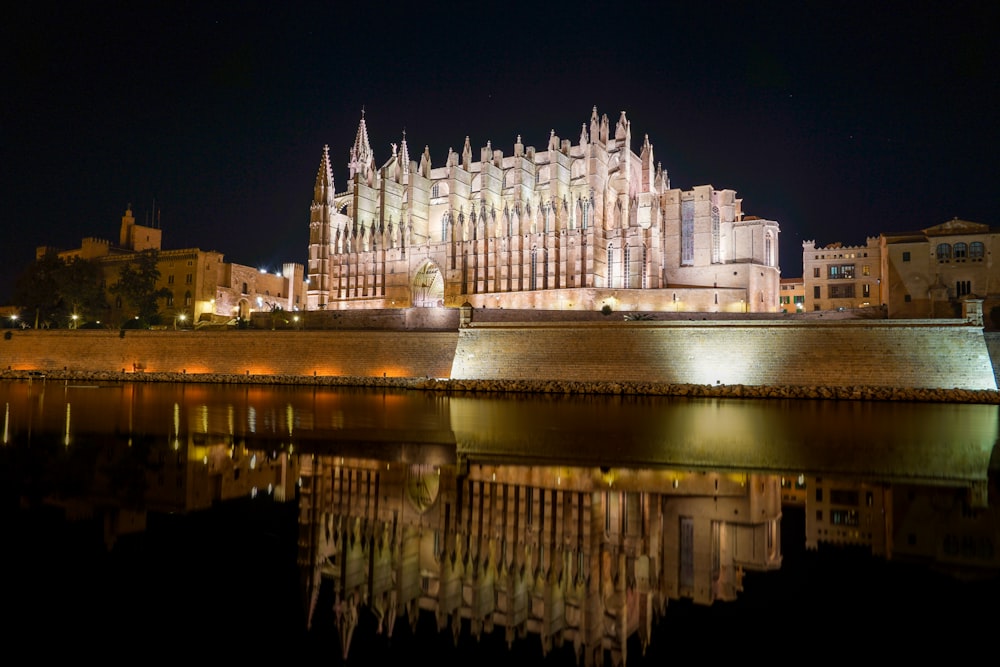 a large cathedral lit up at night next to a body of water