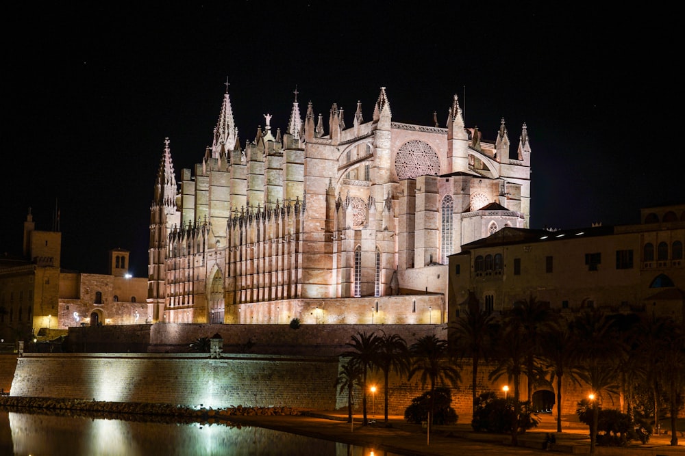 a large cathedral lit up at night next to a body of water