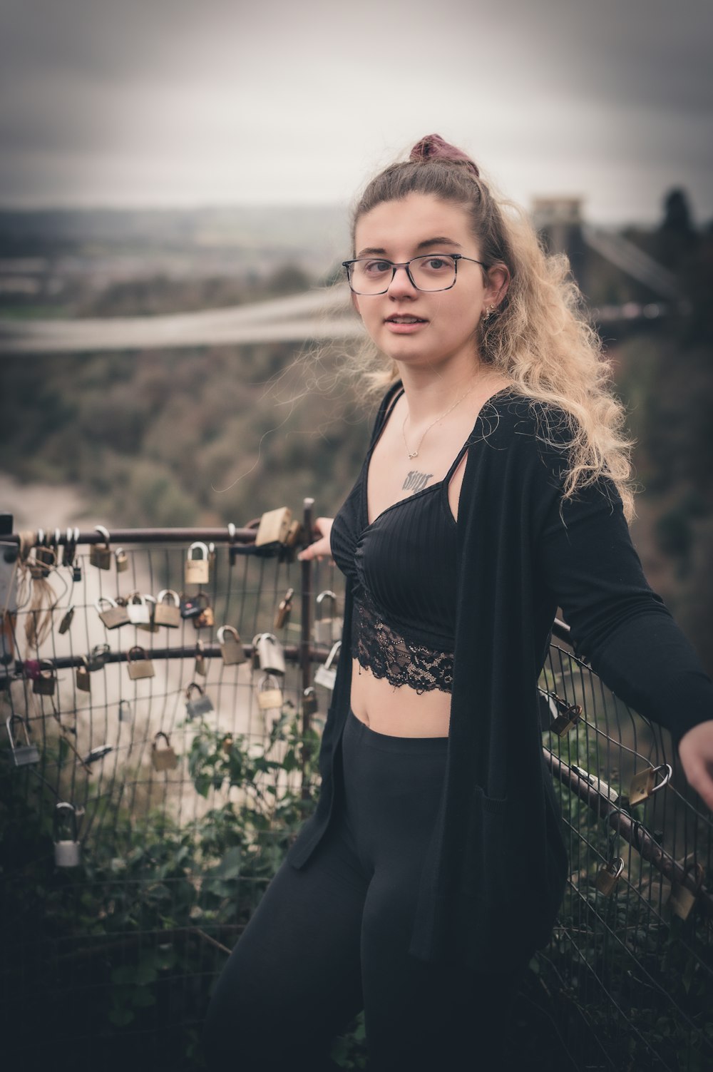 a woman with glasses standing on a bridge