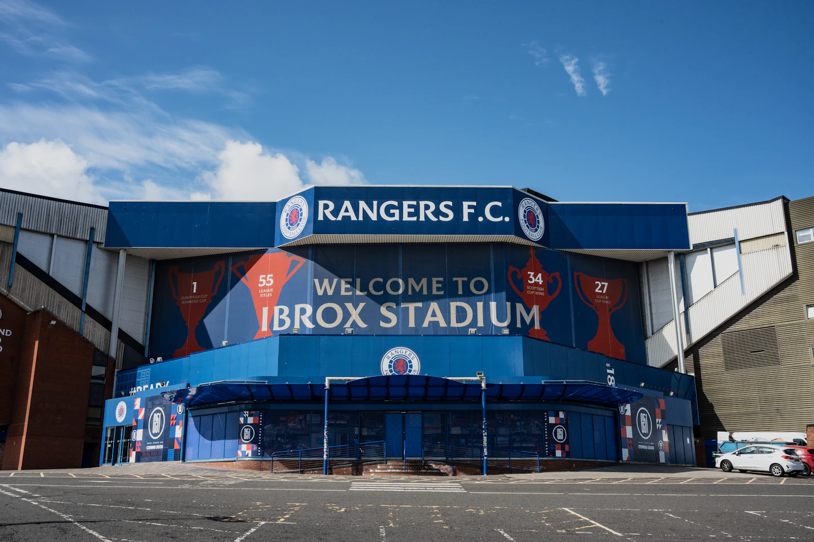 A large stadium building with a welcome sign outside Ibrox Stadium in Glasgow