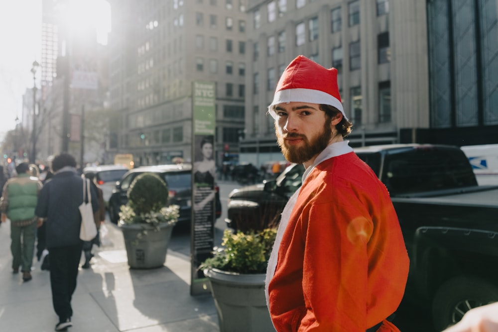 a man in a santa hat is standing on the sidewalk