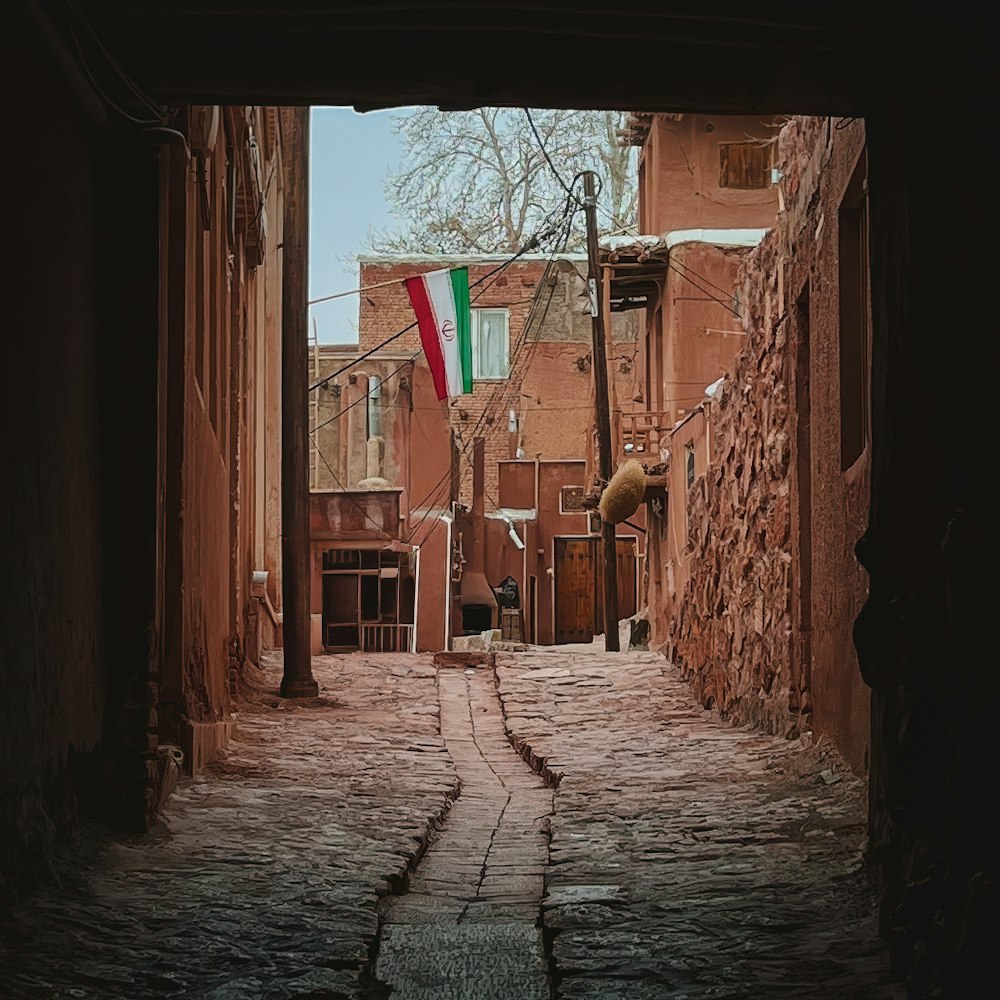 eine schmale Gasse mit einer Fahne an einem Mast