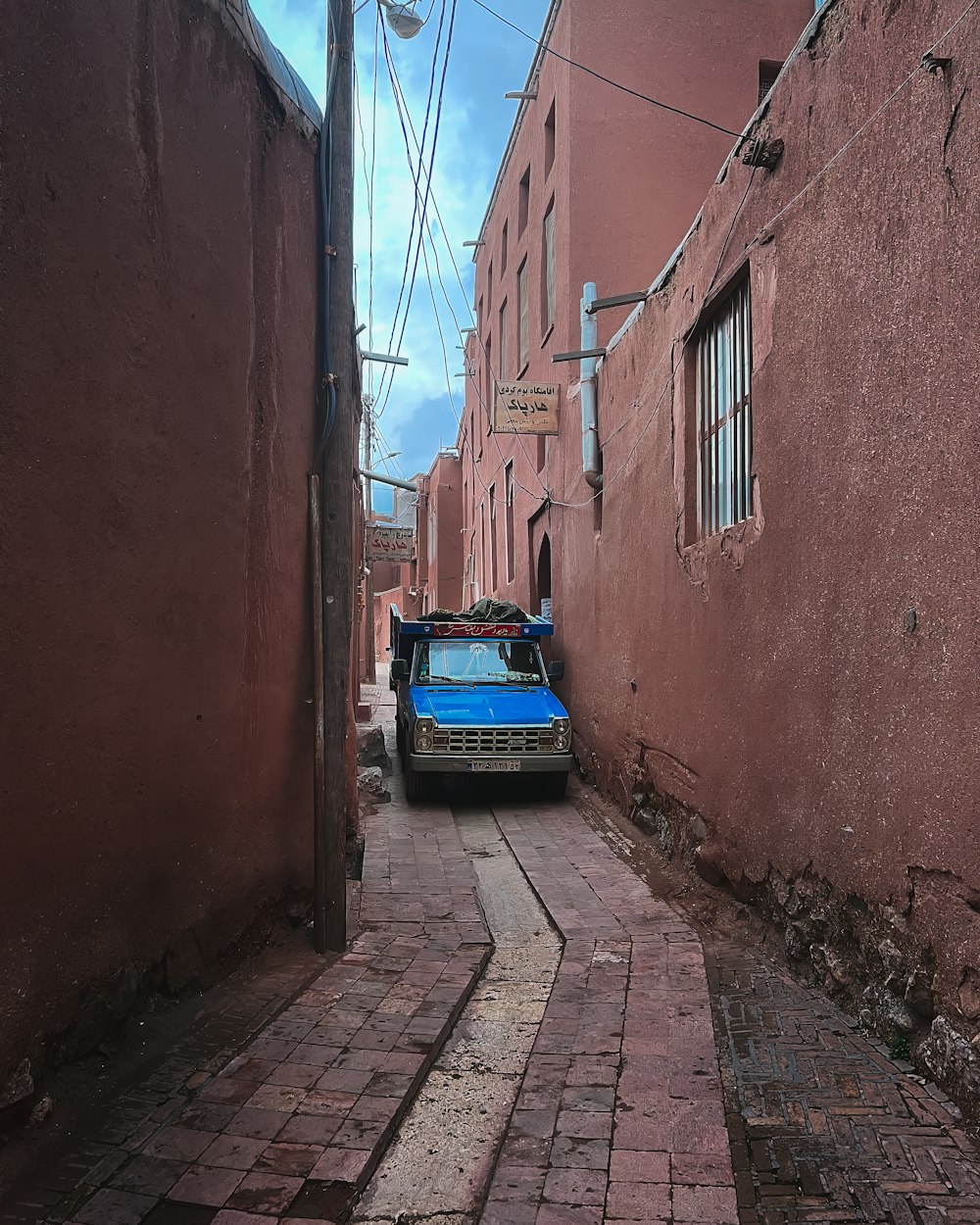a blue truck parked on the side of a brick road