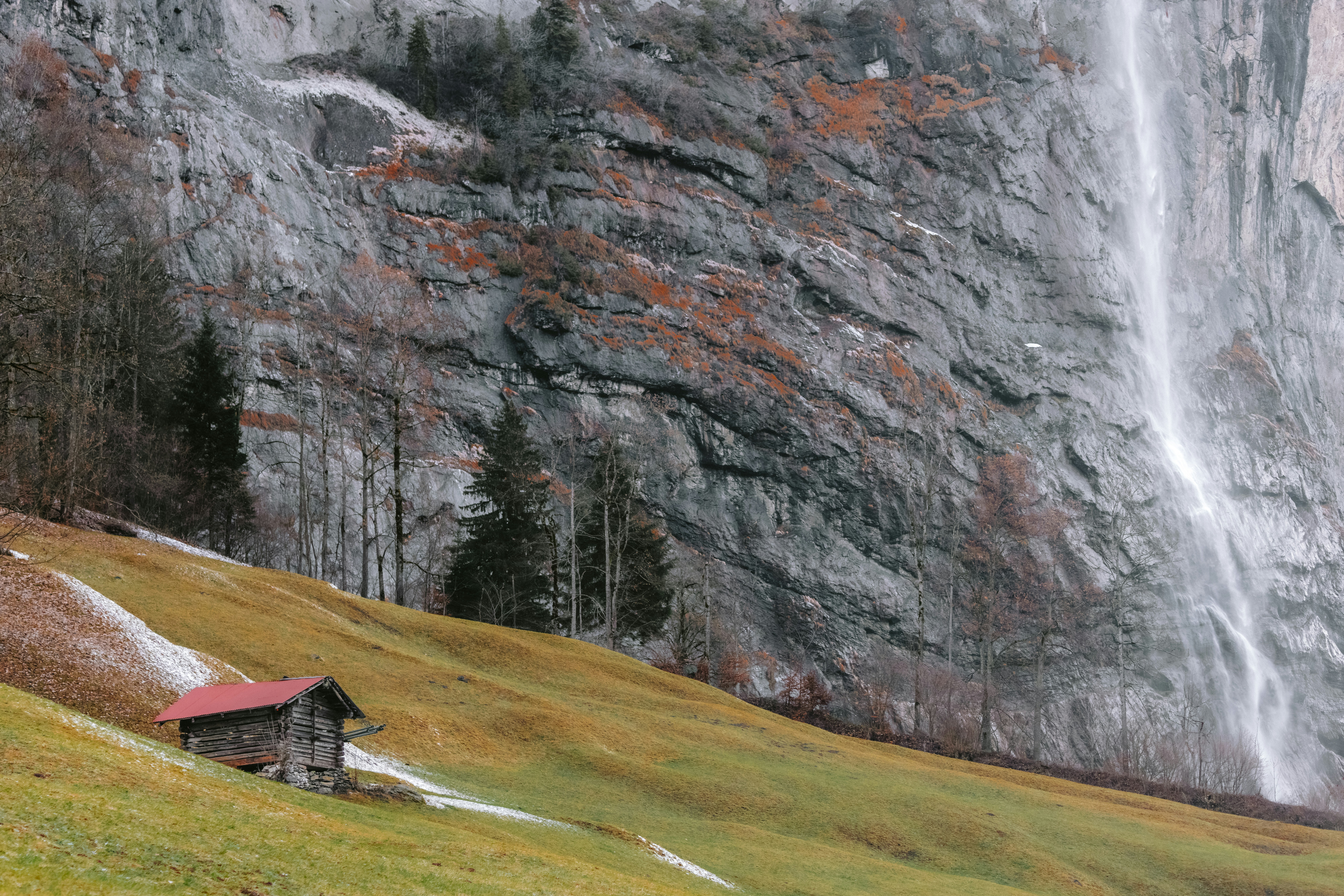 Cabin in a Swiss valley with a waterfall in the background
