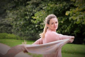 A female model showcasing a pastel pink scarf styled elegantly with a light sweater