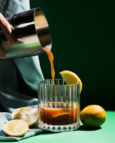 a person pouring orange juice into a glass