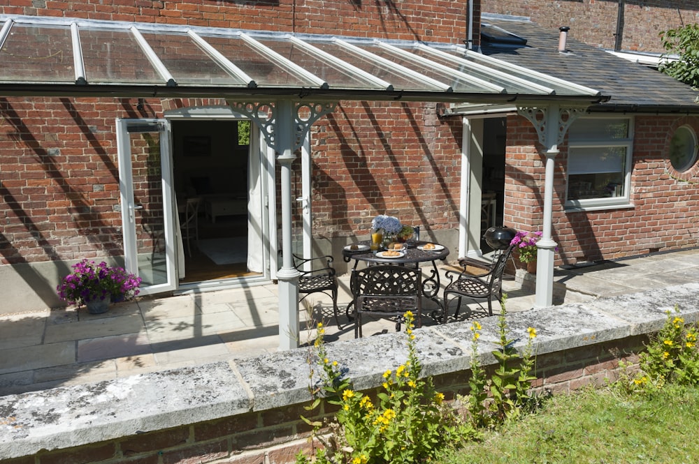 a patio with a table and chairs next to a brick building