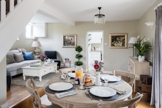 A cozy living room featuring elegant curtains and a beautifully set dining table with a stylish tablecloth.