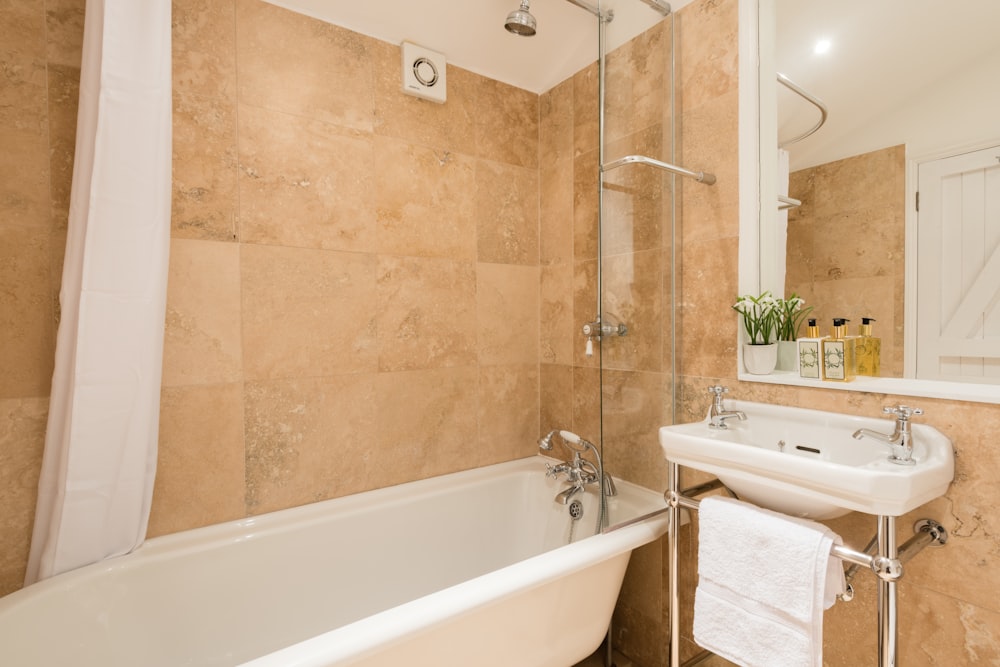 a bathroom with a tub, sink and mirror