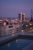 A rooftop pool at sunset overlooking a city's skyline, inviting guests to unwind.