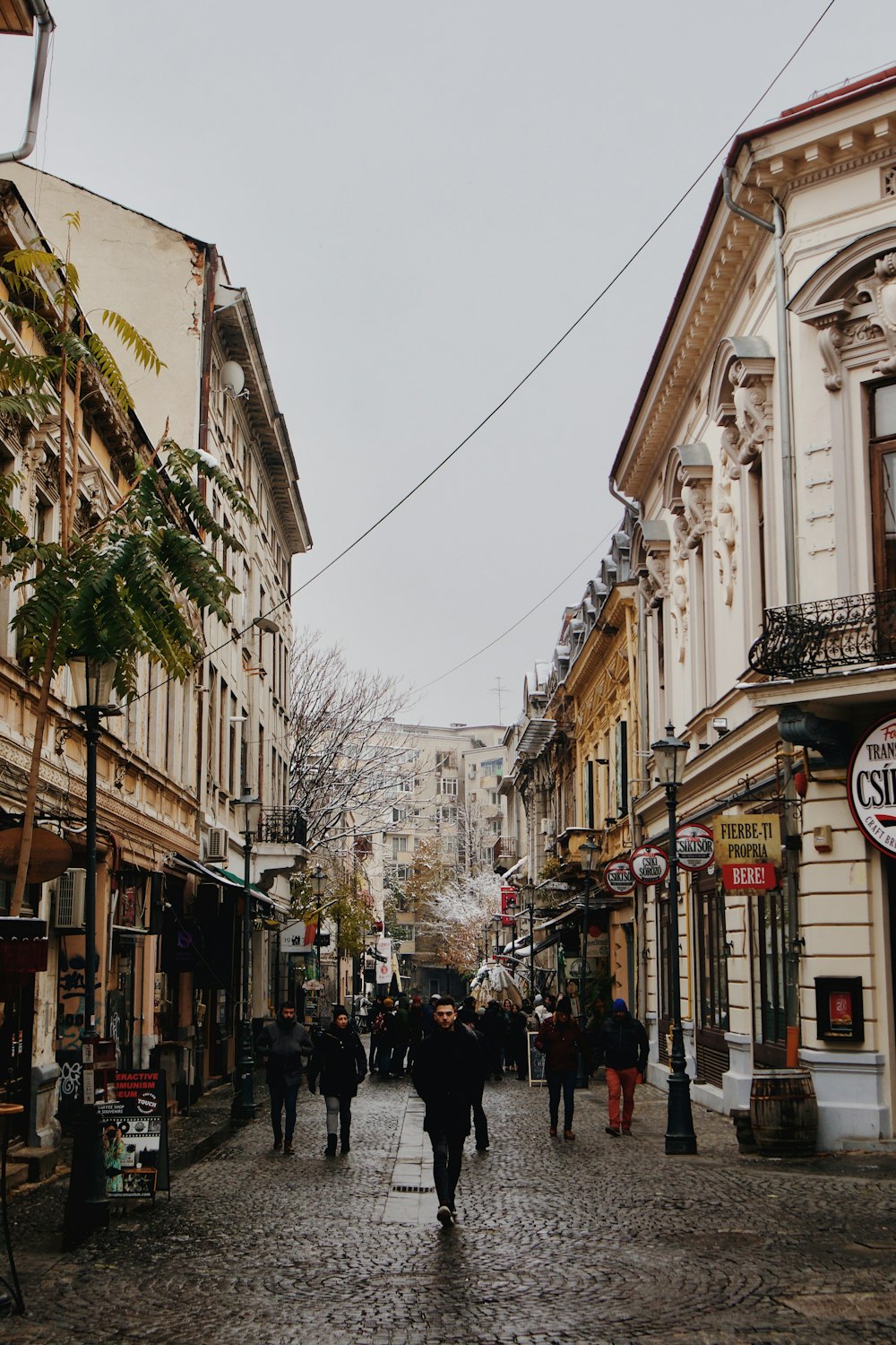 a group of people walking down a street next to tall buildings