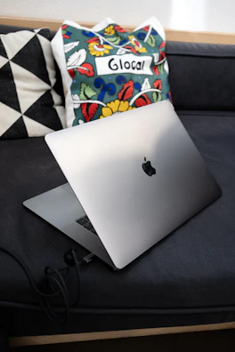 Stylish laptop bag next to a sleek laptop on a cozy couch.