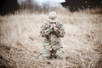 a soldier kneeling in a field praying
