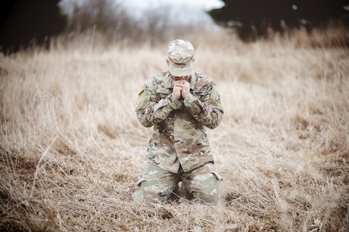 a soldier kneeling in a field praying