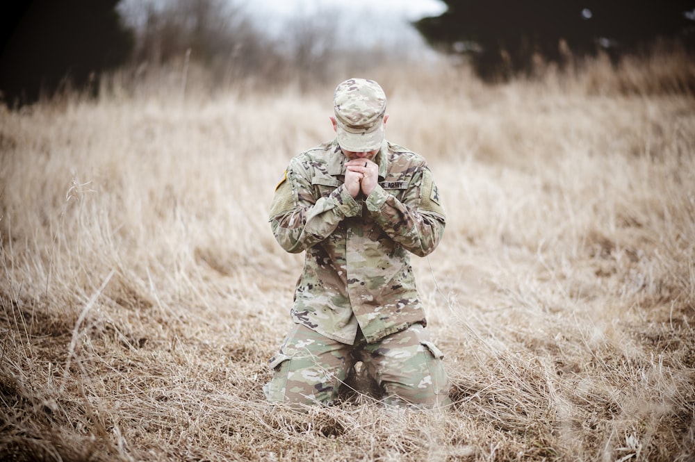 un soldato inginocchiato in un campo a pregare