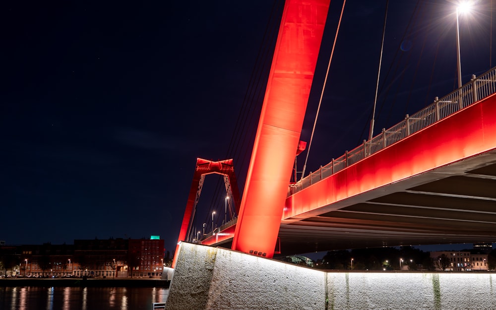 uma ponte iluminada à noite sobre um corpo de água
