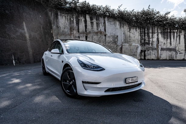 A sleek electric vehicle parked in an urban setting with greenery in the background.