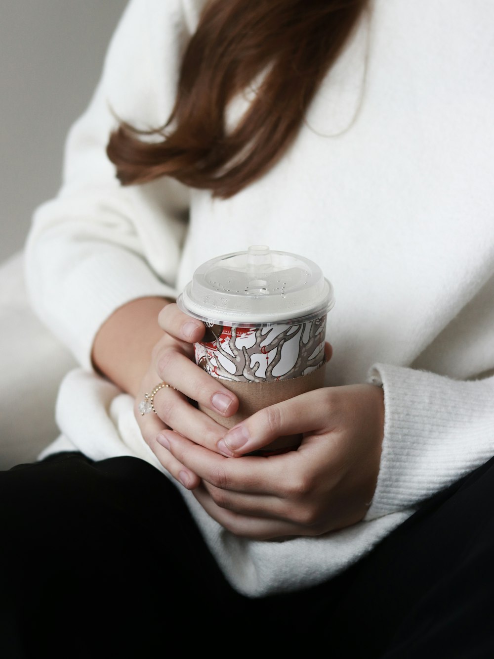 una donna in un maglione bianco che tiene una tazza di caffè