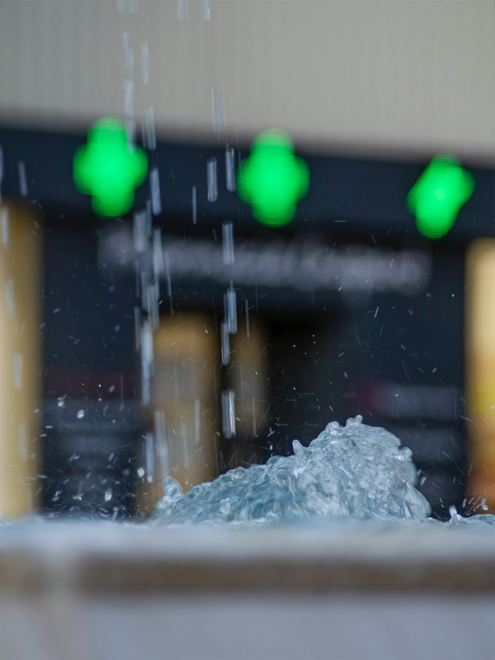 a close up of a water fountain with green lights in the background