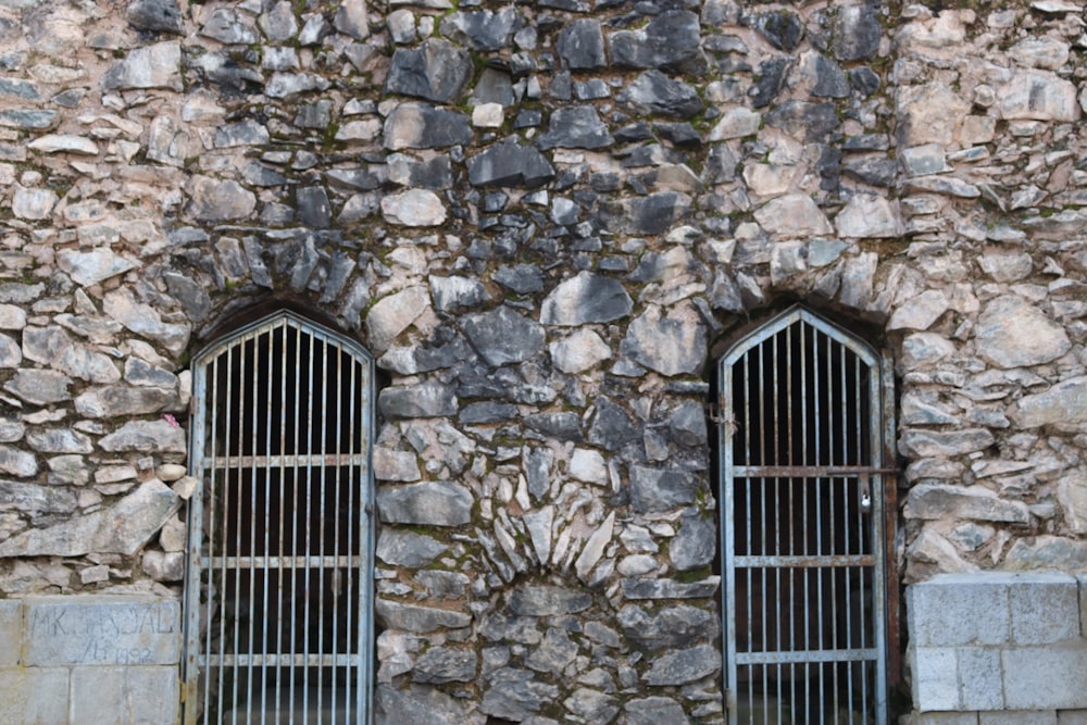 a stone building with two windows and bars