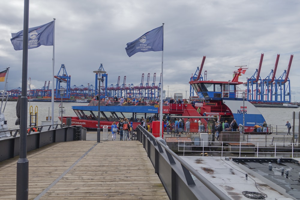 a boat docked at a pier with flags flying in the wind