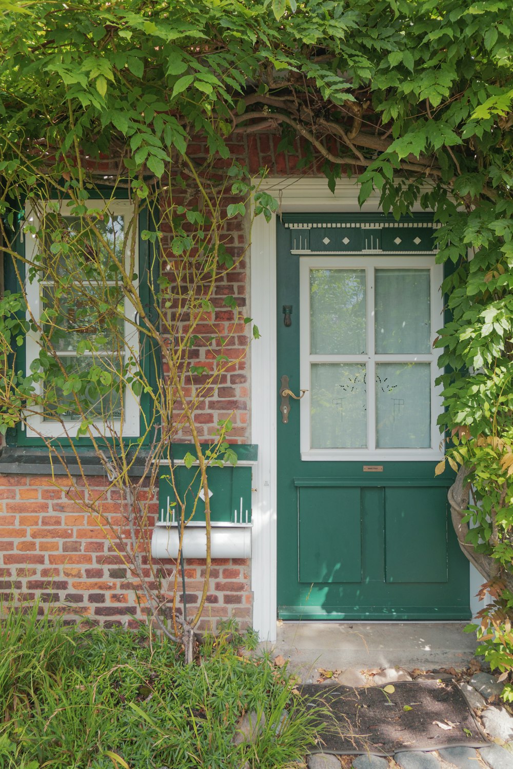 ein Haus mit einer grünen Tür, umgeben von viel Grün