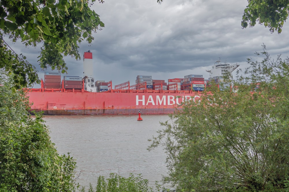 a large red cargo ship sitting on top of a river