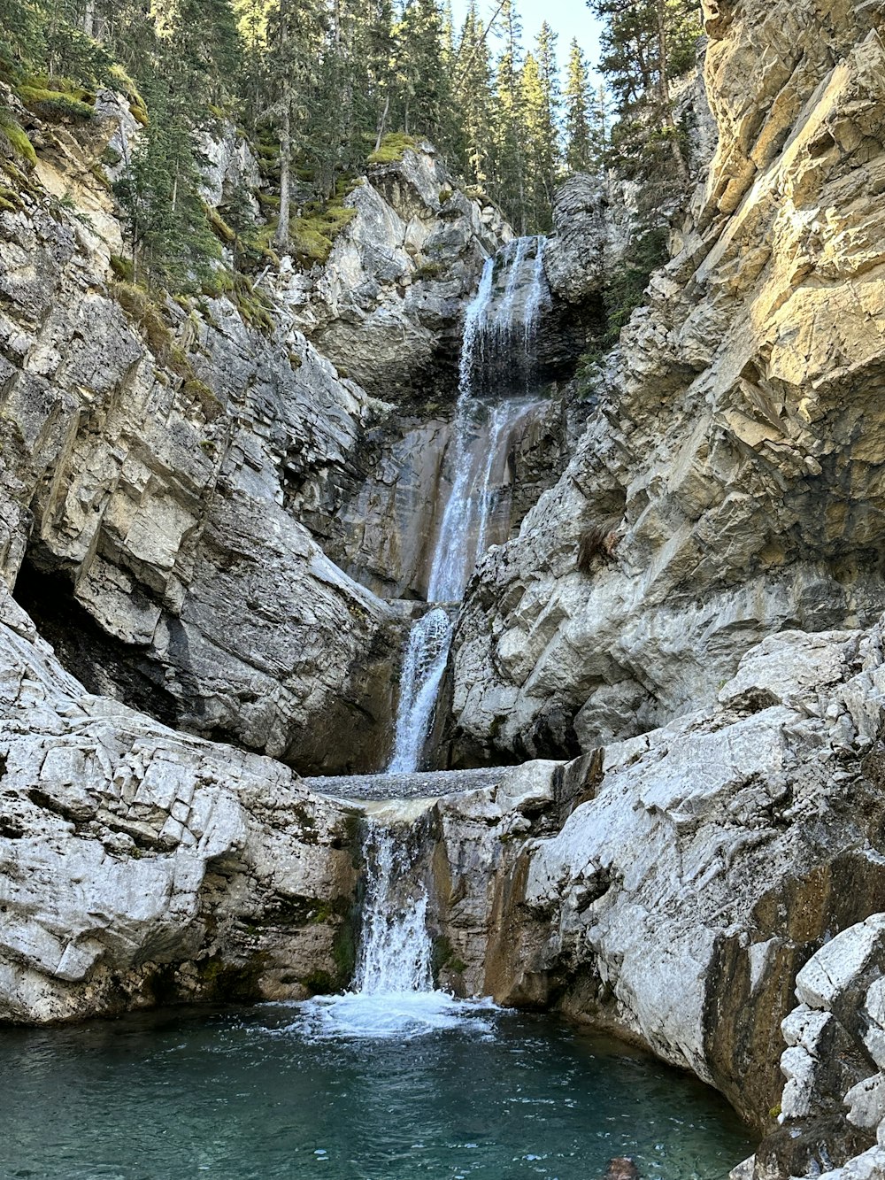 a man swimming in a pool next to a waterfall