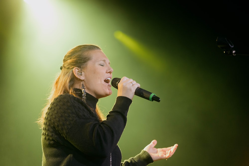 a woman singing into a microphone on stage