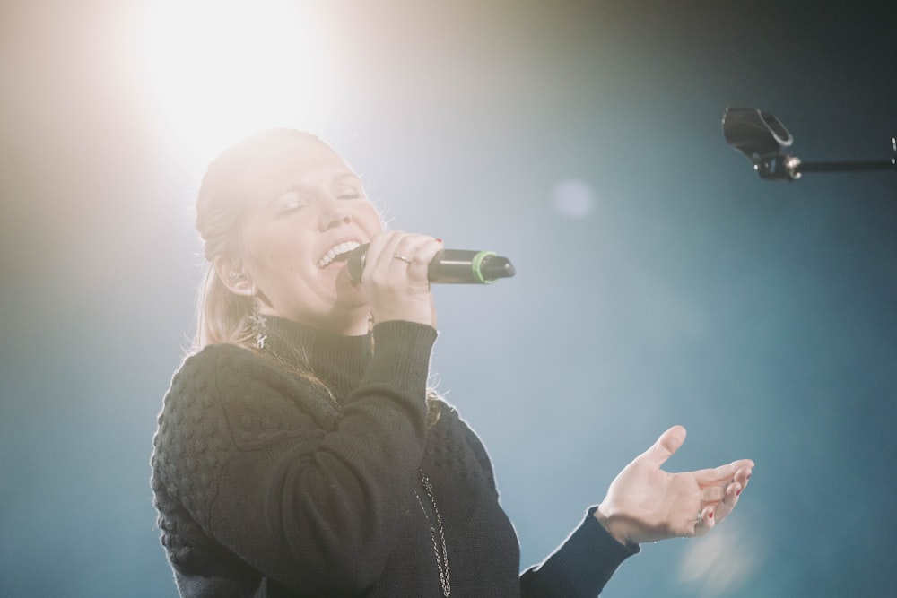 eine Frau, die auf der Bühne in ein Mikrofon singt