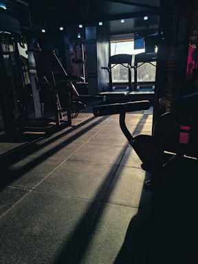 Sunlit gym corner with weights and a yoga mat, framed by warm autumn tones.