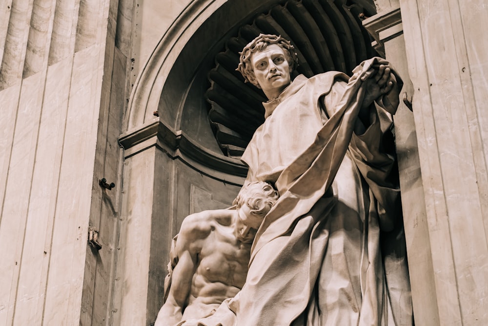 una estatua de un hombre sosteniendo un paño frente a un edificio