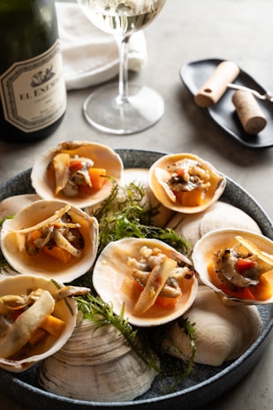 Artistic shot of a shellfish assortment on a rustic wooden table with a glass of white wine.