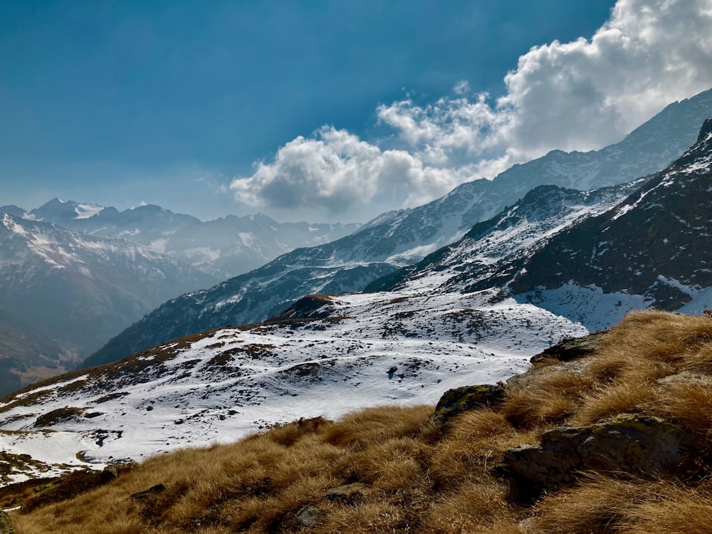 a snow covered mountain range with a few clouds in the sky