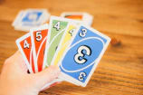 A close-up of Uno cards fanned out in a player's hands mid-game.