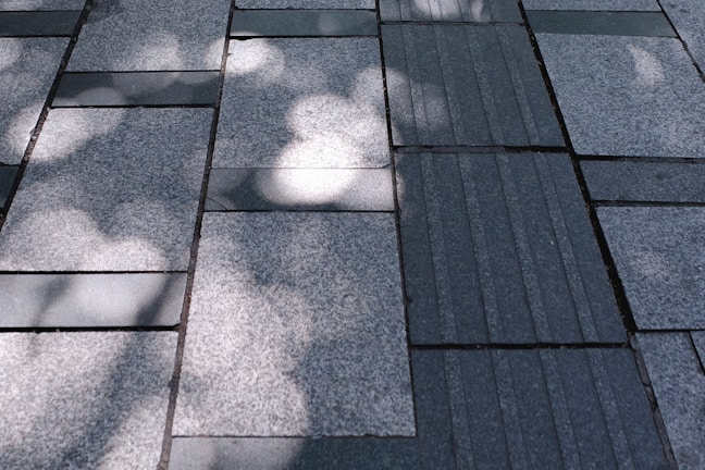 A freshly installed patterned stone driveway glistening under soft sunlight.