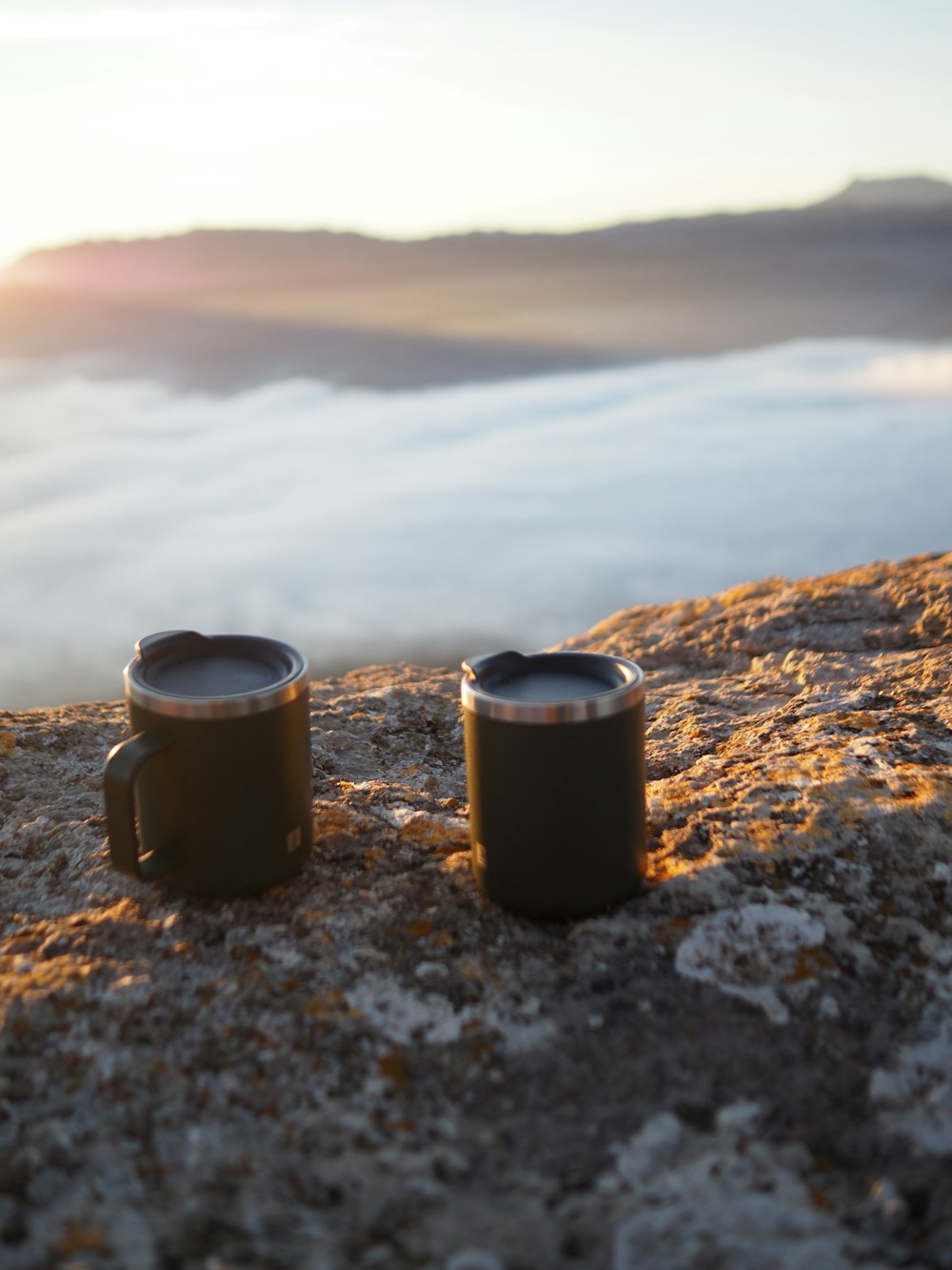 zwei Kaffeetassen sitzen auf dem Gipfel eines Berges