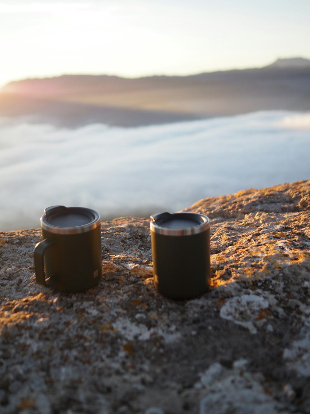 산 꼭대기에 앉아있는 두 개의 커피 머그잔