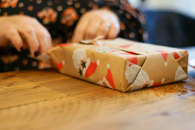 Close-up of hands packing a customized Christmas hamper with care and attention.
