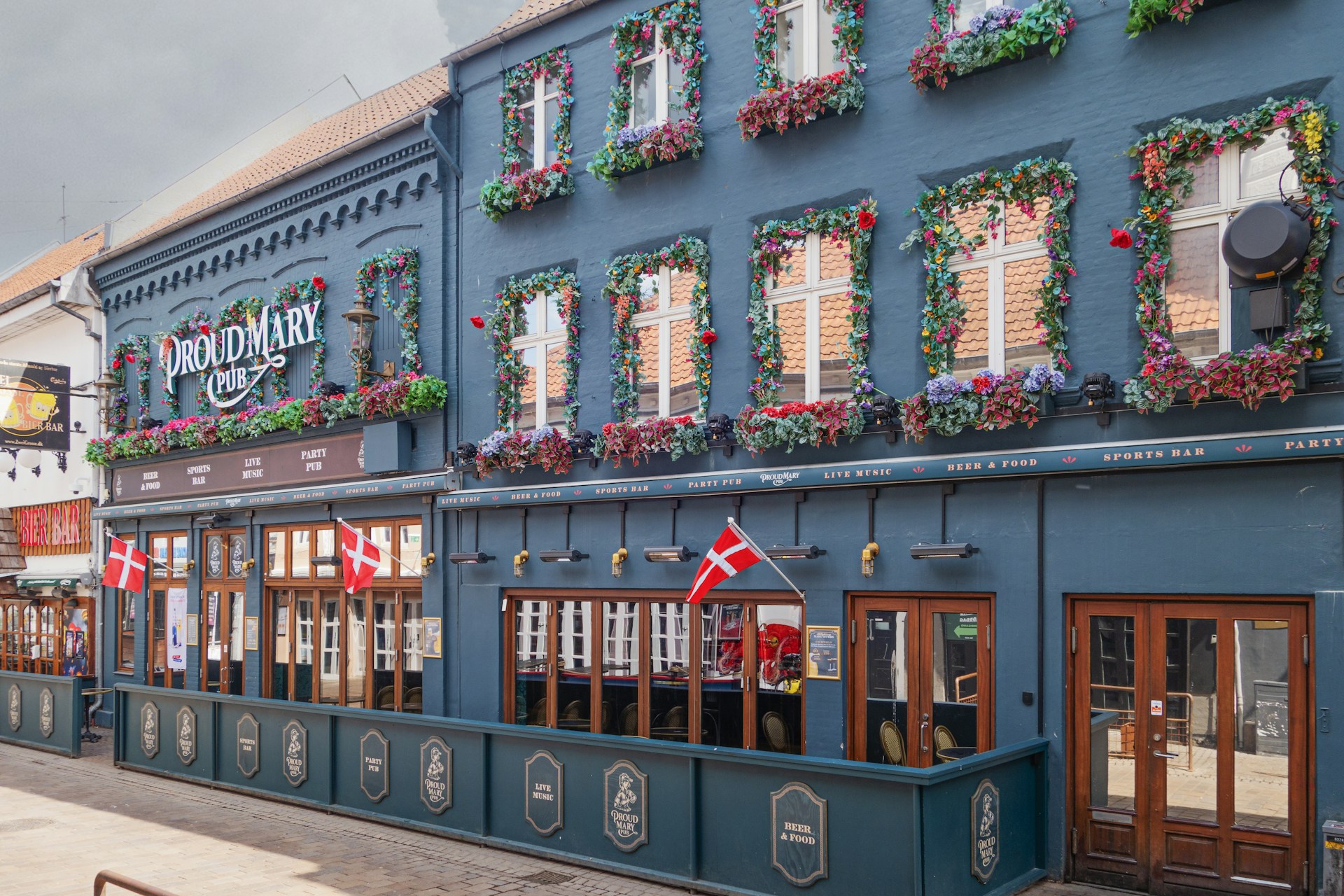 a blue building with many windows and flowers on it
