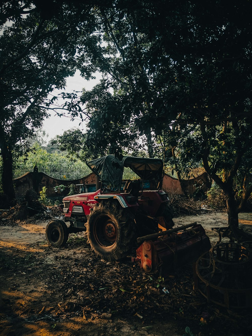 a red tractor parked in front of a tree