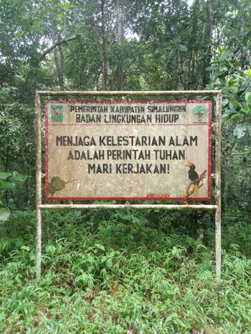 An indigenous leader speaking passionately at a community gathering in Riau province, surrounded by lush forest.