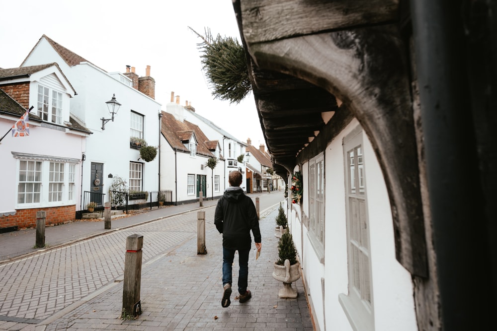 a man walking down a street next to white buildings