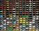 A collection of miniature toy vehicles arranged neatly in a grid of shelves. Various models of cars, vans, and scooters are displayed, featuring a wide range of vibrant colors.