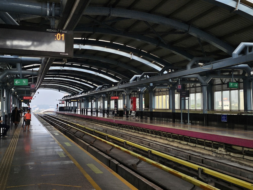 uma estação de trem com pessoas esperando pelo trem