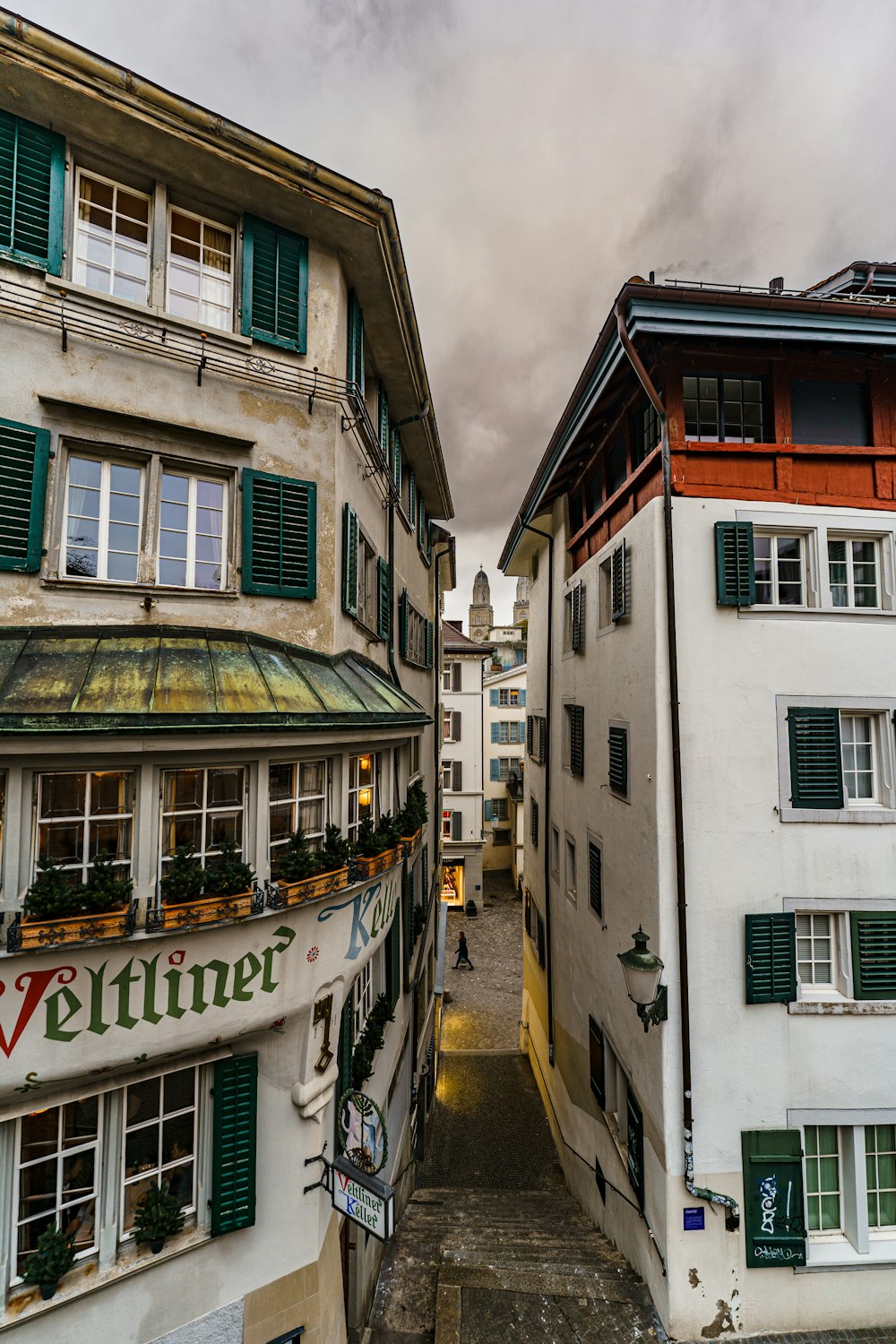 a narrow alley way between two buildings with green shutters