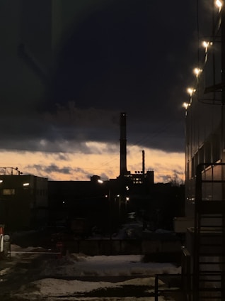 Technicians discussing plans on an industrial site with heavy machinery in the background during sunset.