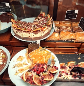 A colorful assortment of gluten-free cakes decorated with fresh fruits and nuts.