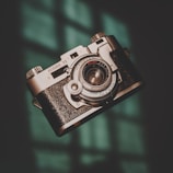A vintage Kodak 35 camera is prominently featured, with intricate metallic details and a textured grip, set against a softly lit background with a hint of teal.