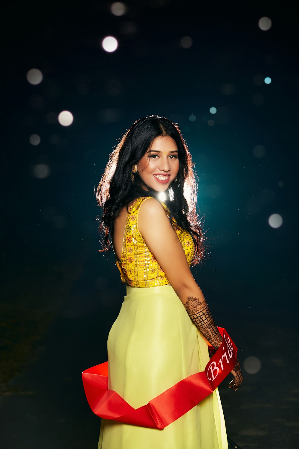 a woman in a yellow dress holding a red ribbon